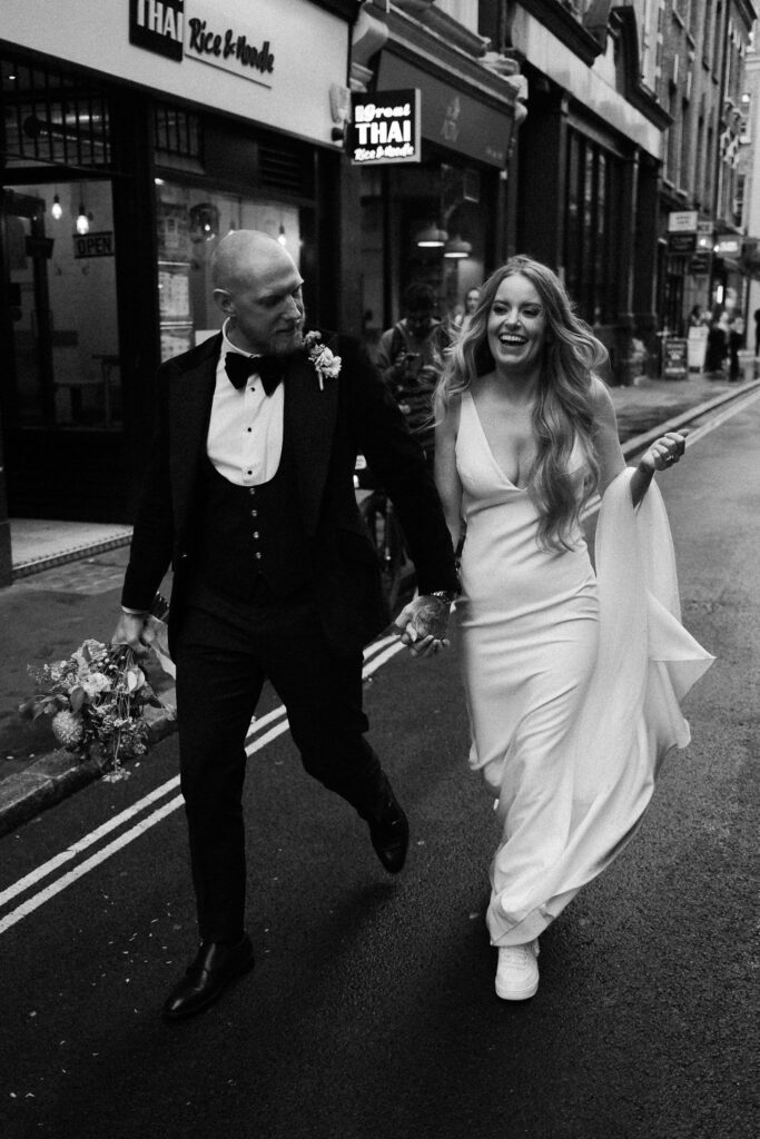 Bride and groom walk through Soho on their wedding day.