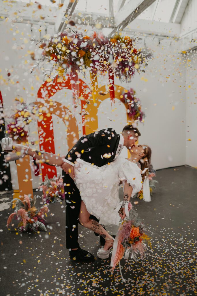 Tattooed bride and groom kiss as confetti falls on them at their alternative wedding in Melbourne.