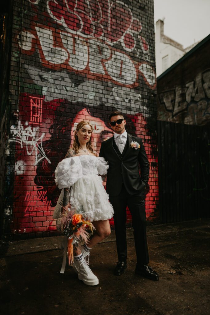 tattooed bride wearing a short wedding dress with her groom in Digbeth for their alternative wedding. 