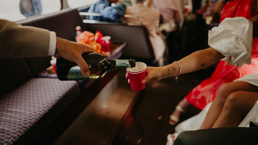 Pouring champagne on a red London Wedding bus.