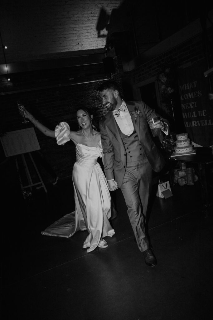 Bride and groom walk into their wedding breakfast at Shoreditch Studios.