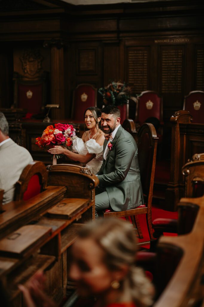 Bride and groom listen to a reading at their wedding at Islington Town Hall.