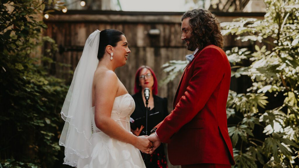 A bride and groom hold hands during their wedding ceremony in London.