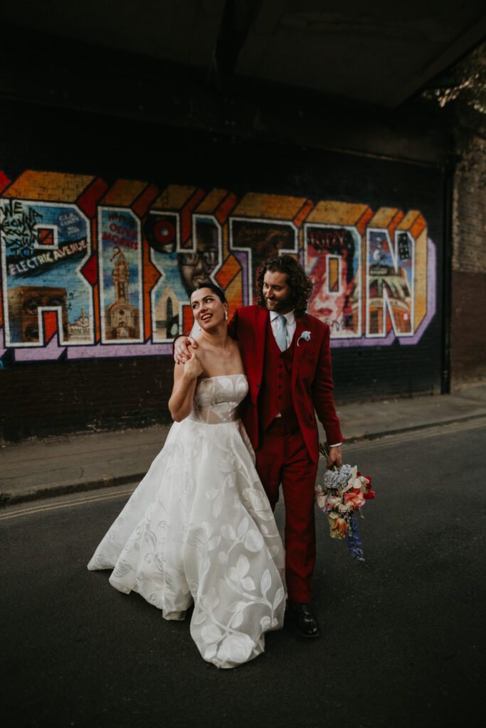 Bride and groom walk past the Brixton mural on their wedding day.