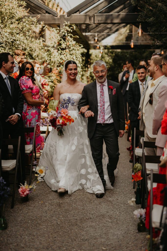 A bride is walked down the aisle by her father at 100 Barrington.