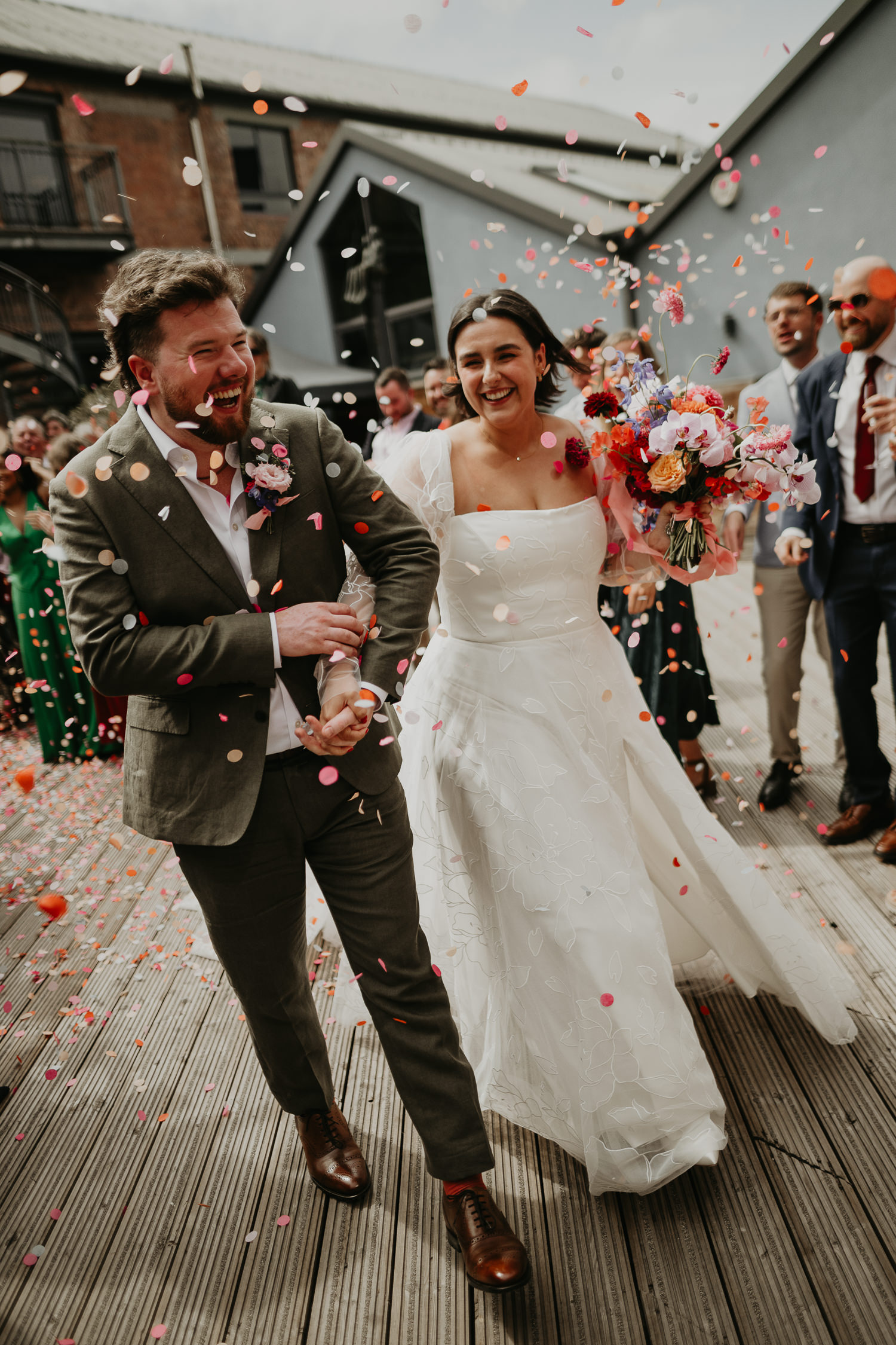 Wedding guests throw confetti at a bride and groom at their wedding at at Paintworks in Bristol.