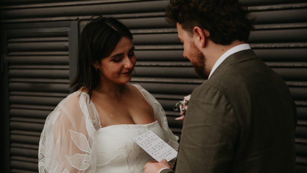 Groom reads personal vows to his bride during their couples portraits at The Paintworks in Bristol.  