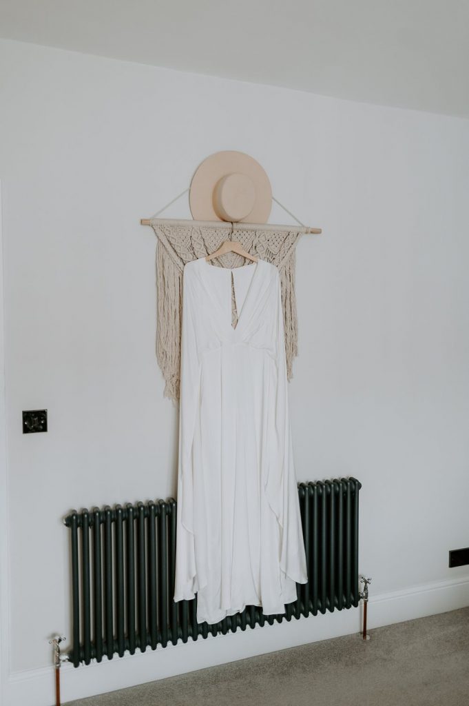 A wide brimmed hat from Lack of Color Aus hangs from the wall with a boho wedding dress.