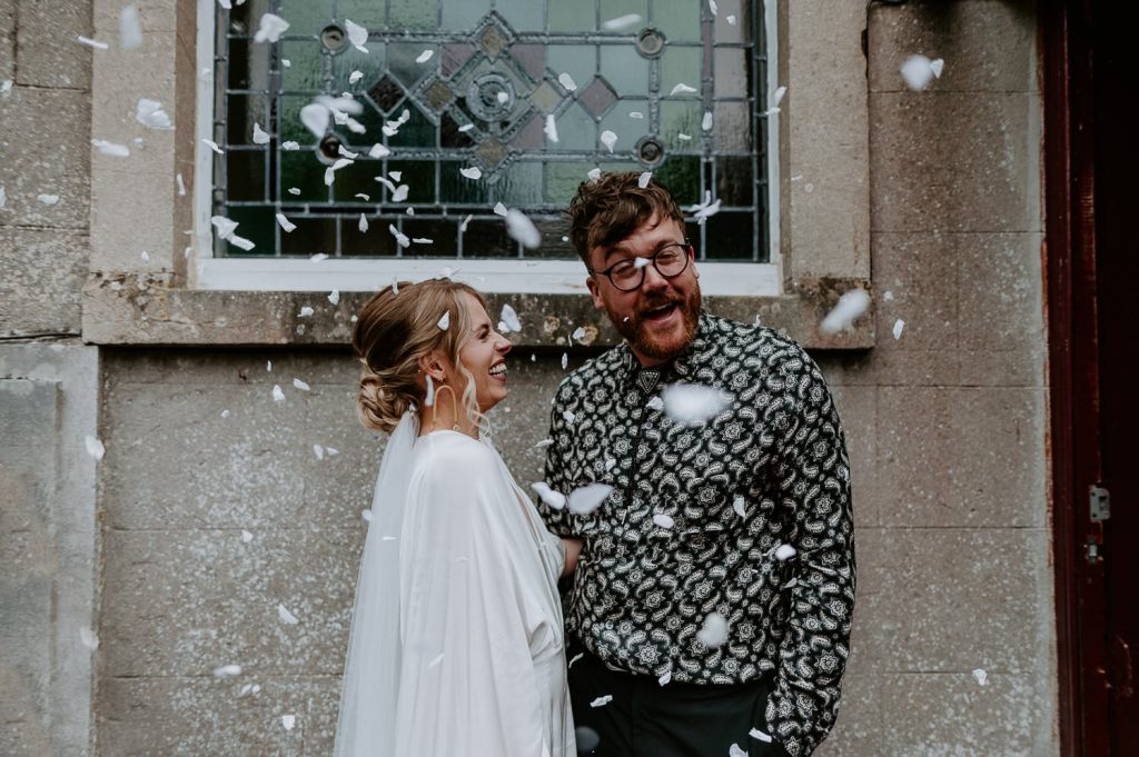 A bride and groom are covered in confetti outside their wedding venue in Bristol.