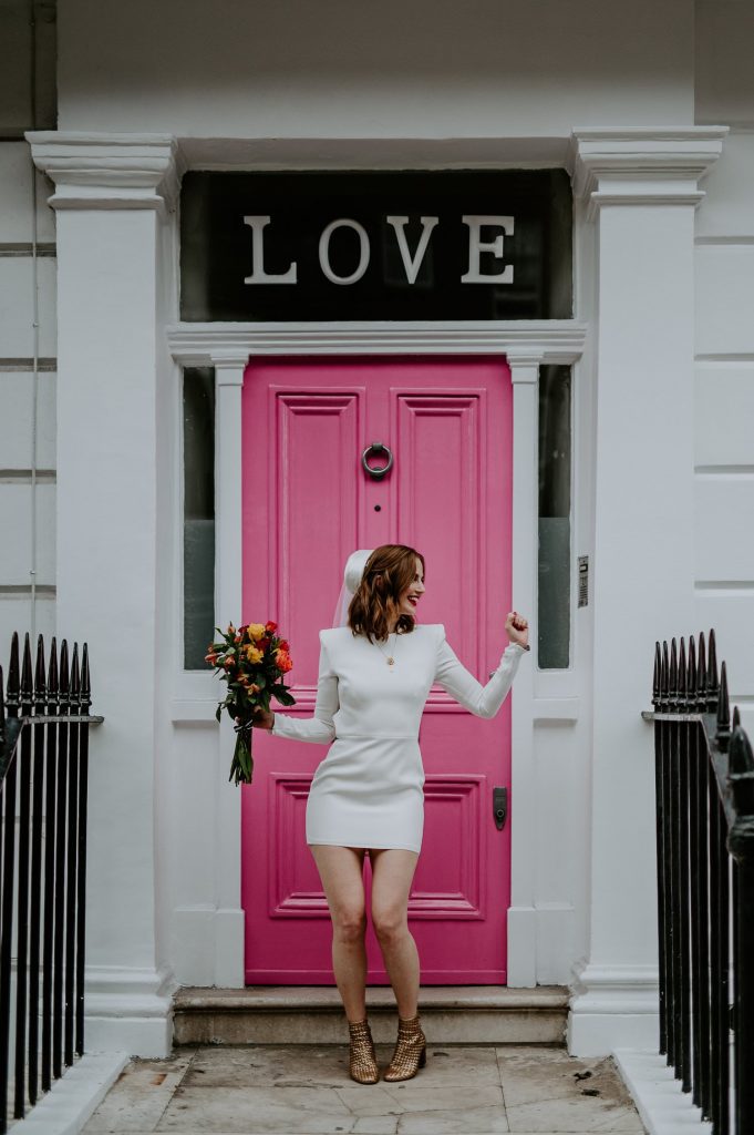 A bride dances in front of the pink LOVE door near Chelsea in London.