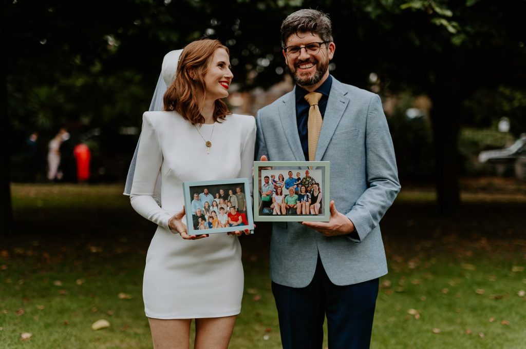 A wedding couple hold up photos of their family.