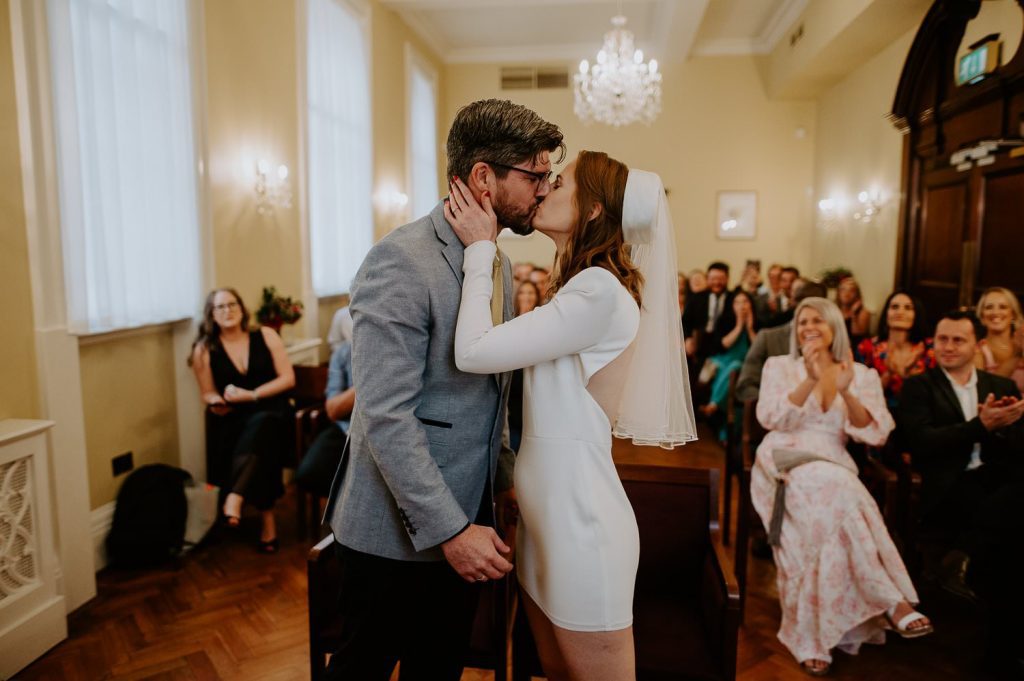 A bride and groom kiss at their ceremony at Chelsea Town Hall.