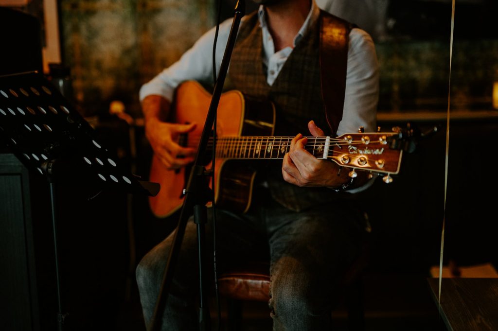 A shot of a guitar payer playing an acoustic guitar a a reception at The Great Guns in London.