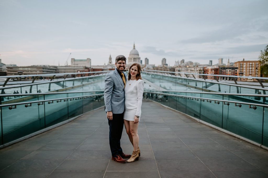 A bride and groom on Millennium Bridge with St Pauls Cathedral in the background in London.