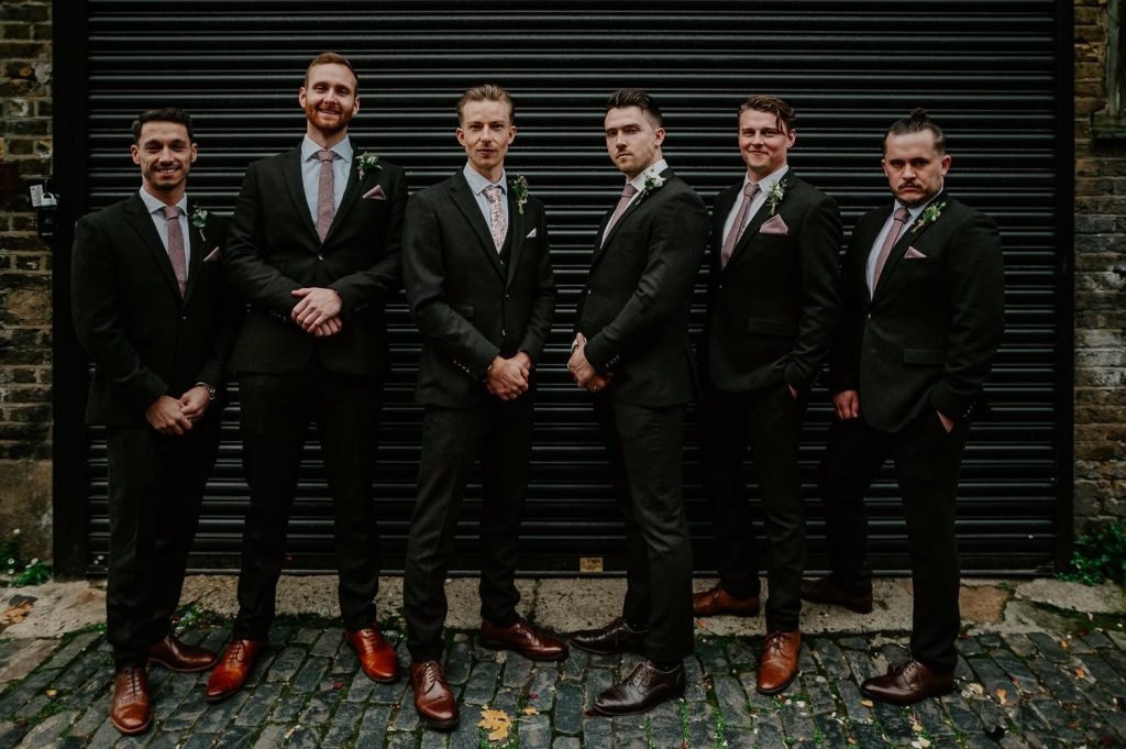 Groomsmen in front of a black shutter at Clapton Country Club.