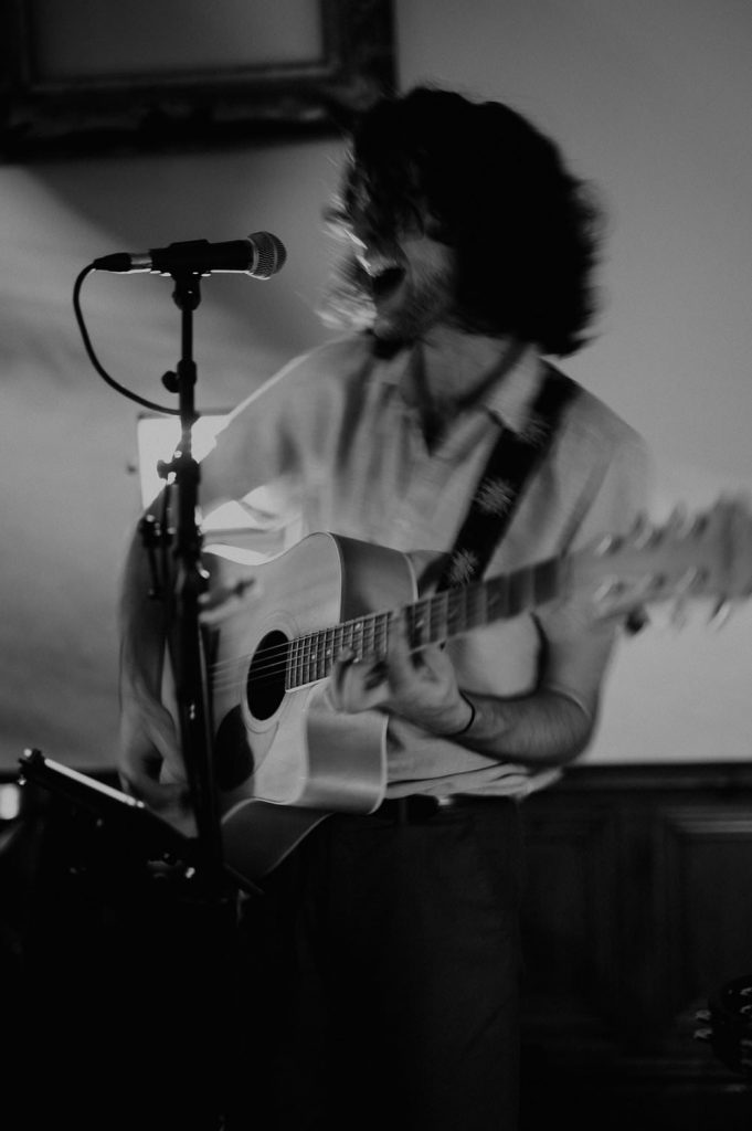 A slow shutter photo of a guitarist paying an acoustic guitar at a wedding reception.