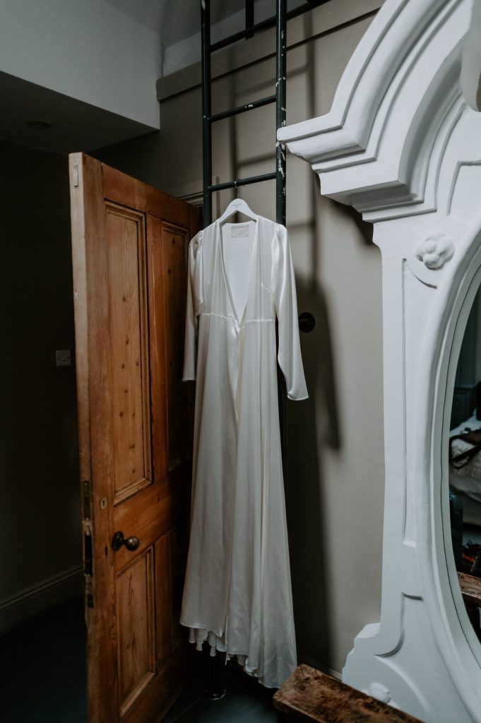 A White Wedding dress hung up behind a door.