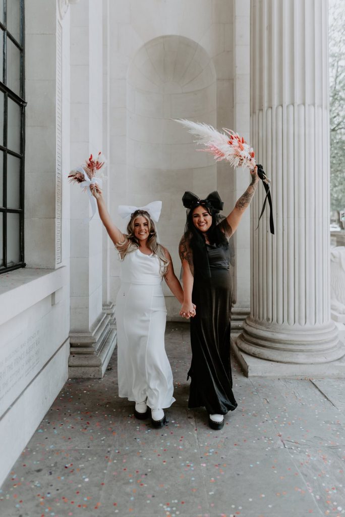 Two brides walk through the alcoves at Marylebone Town Hall