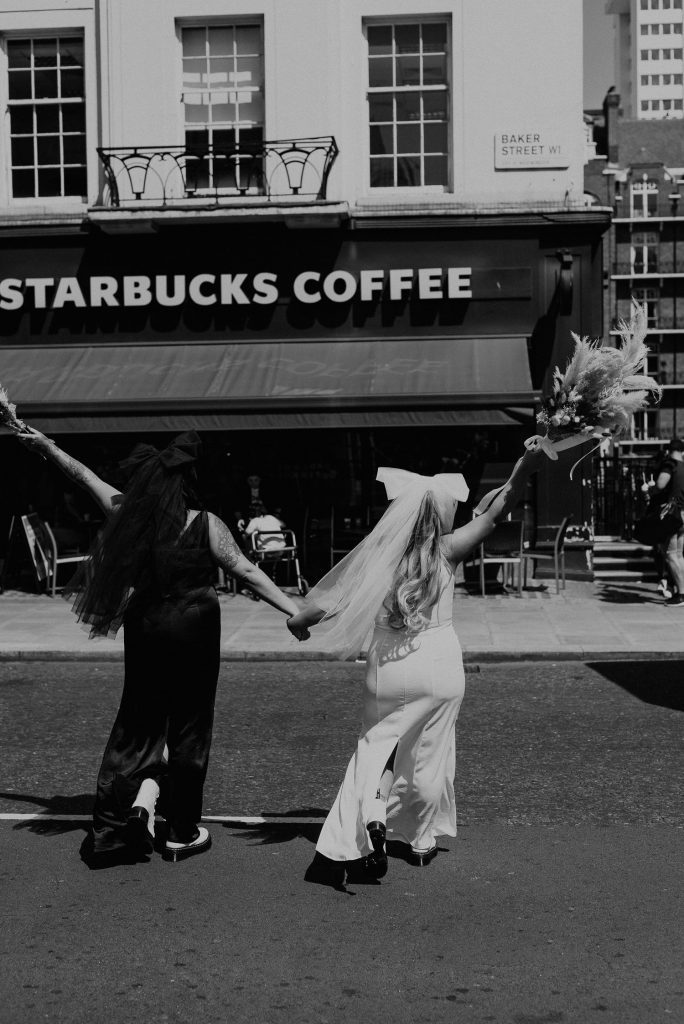 Two brides walk towards a London Starbucks.