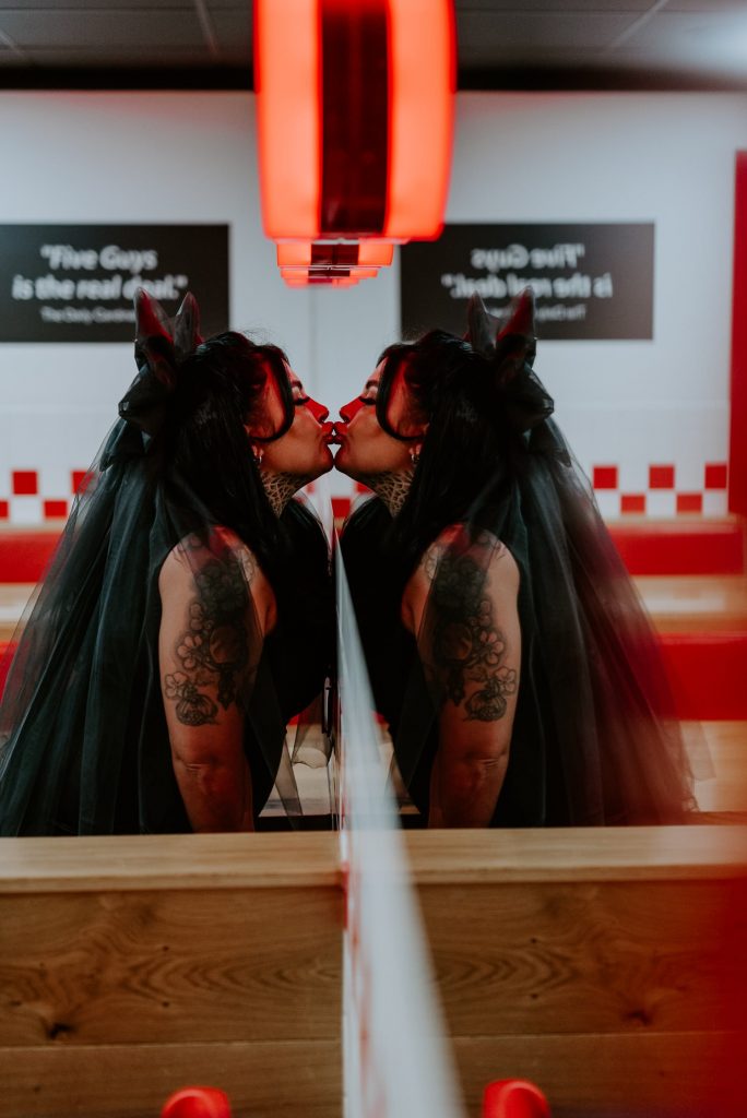 A bride kisses her reflection in the mirror at an American Diner.