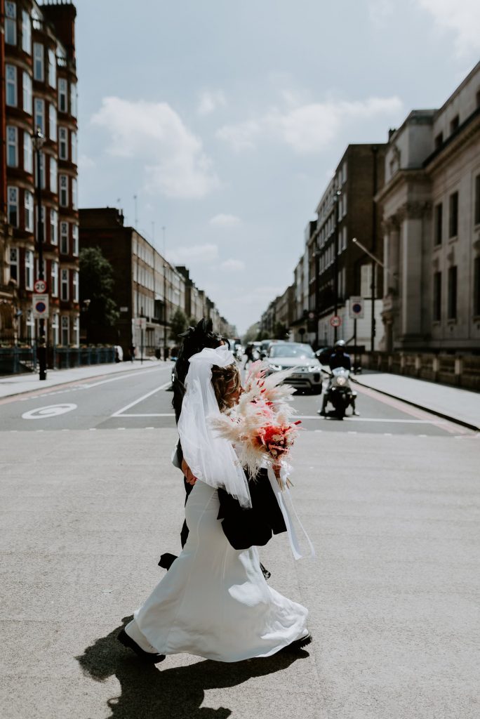 Two brides cross the road on the way to their wedding at the old Marylebone Town Hall in London