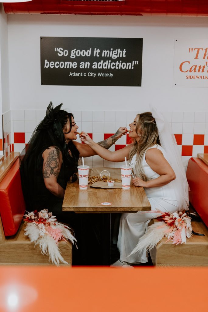 A same sex couple share fries at an American Diner on their wedding sat in London.
