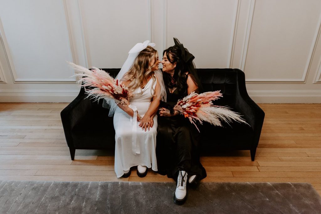Two brides sit for photos after their ceremony at the old Marylebone Town Hall.