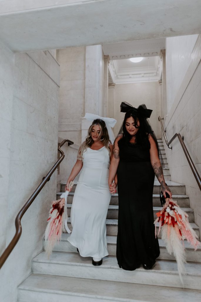 Two brides walk down the stairs at Marylebone Town Hall
