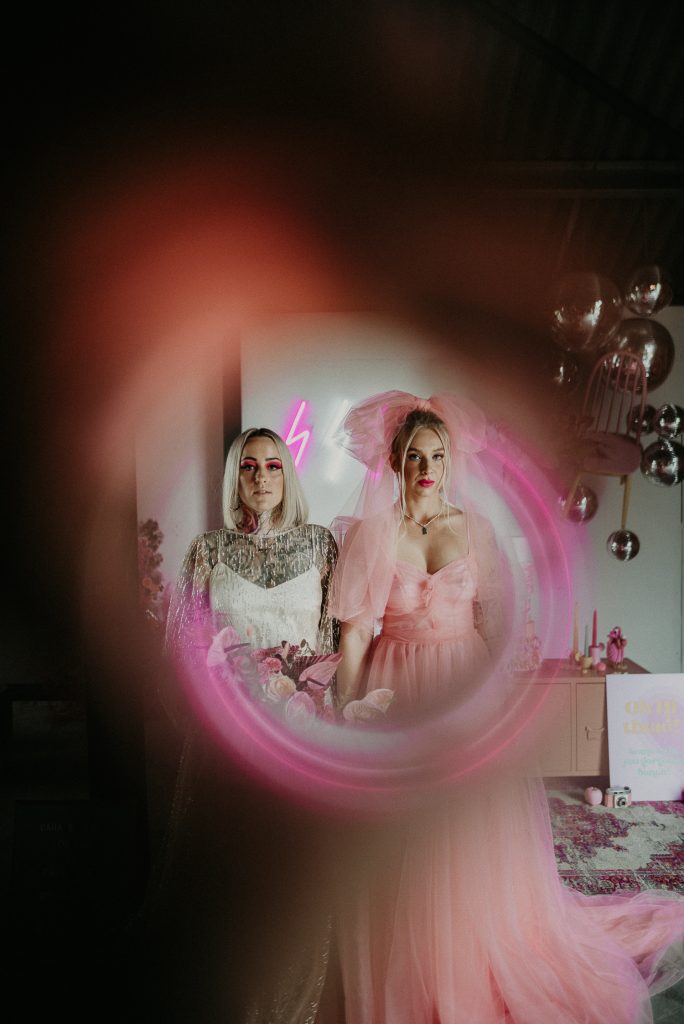 Two brides at the giraffe shed shot through a copper pipe creating a cool pink effect.