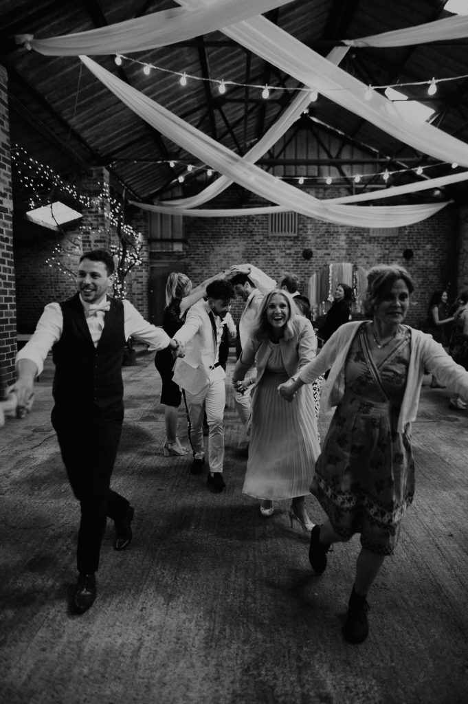 Wedding guests all dance in a line to a Ceilidh band at White Syke Fields.