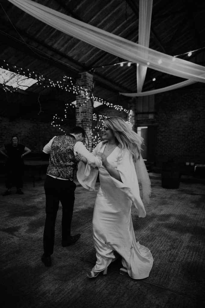 A bride and groom swing each other around to a Ceilidh band at their wedding at White Syke Fields.