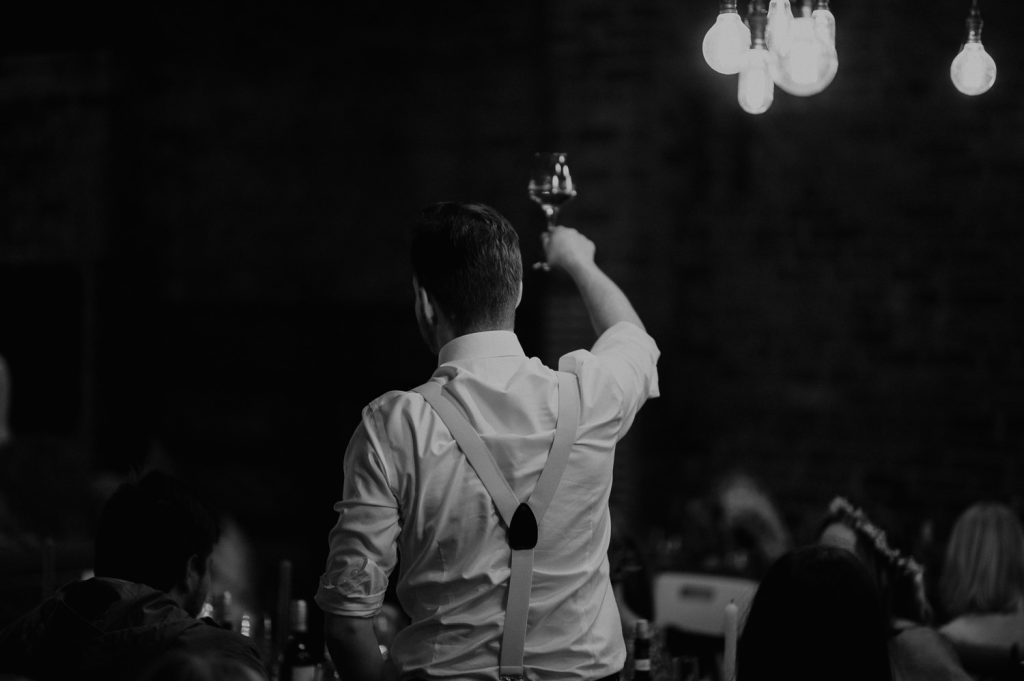 A shot of the best man from behind as he raises his glass at the end of his speech at White Syke Fields.