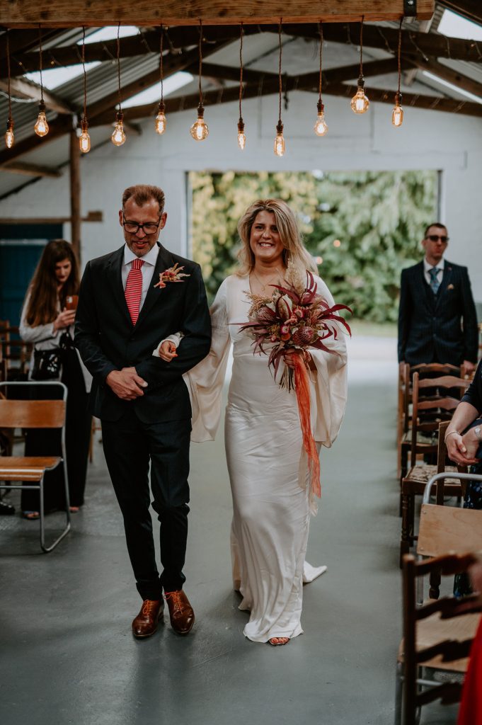 A bride walks down the aisle with her Dad at White Syke Fields barn wedding venue.