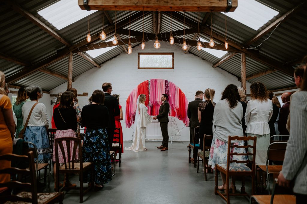 A wide shot down the aisle of a bride and groom changing vows at White Syke Fields in York.