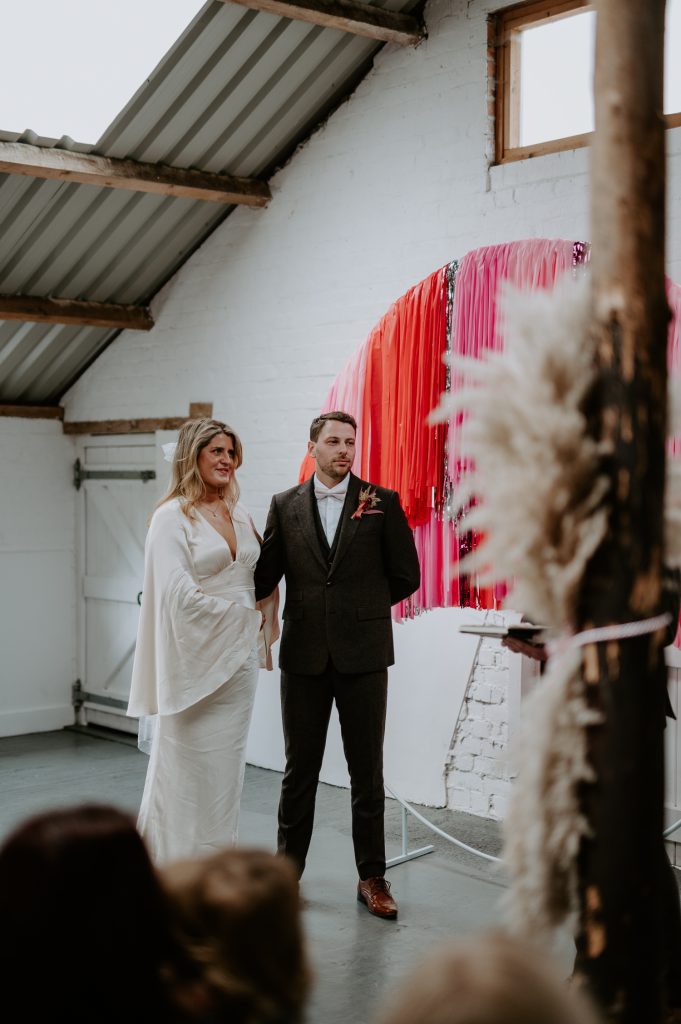 A bride and groom listen to their celebrant lead their ceremony at White Syke Fields.