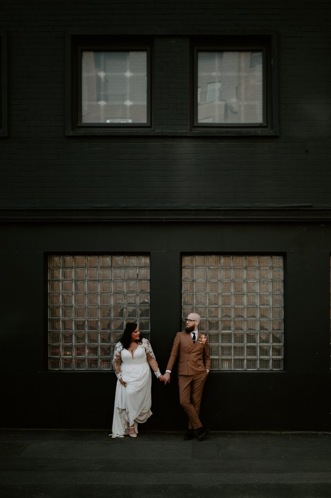 A bride and groom stood outside Five Four Studios black exterior in Manchester.