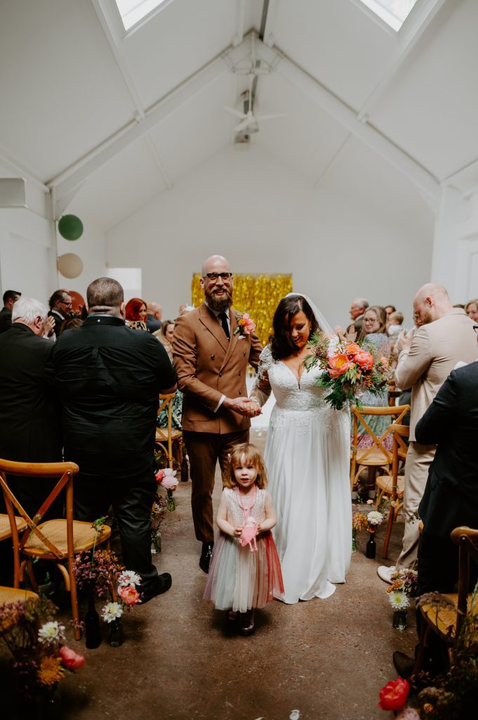 A bride and groom walk back up the aisle at their wedding at Five Four Studios in Manchester.