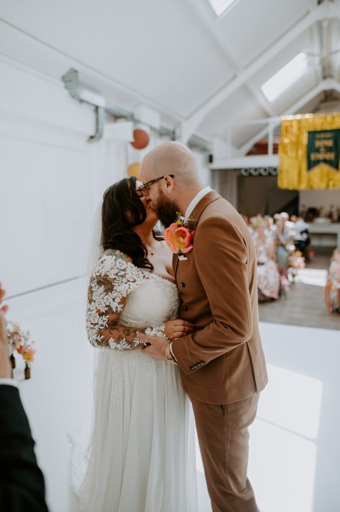 The first kiss of a bride and groom at their stylishly colourful wedding at Five Four Studios.