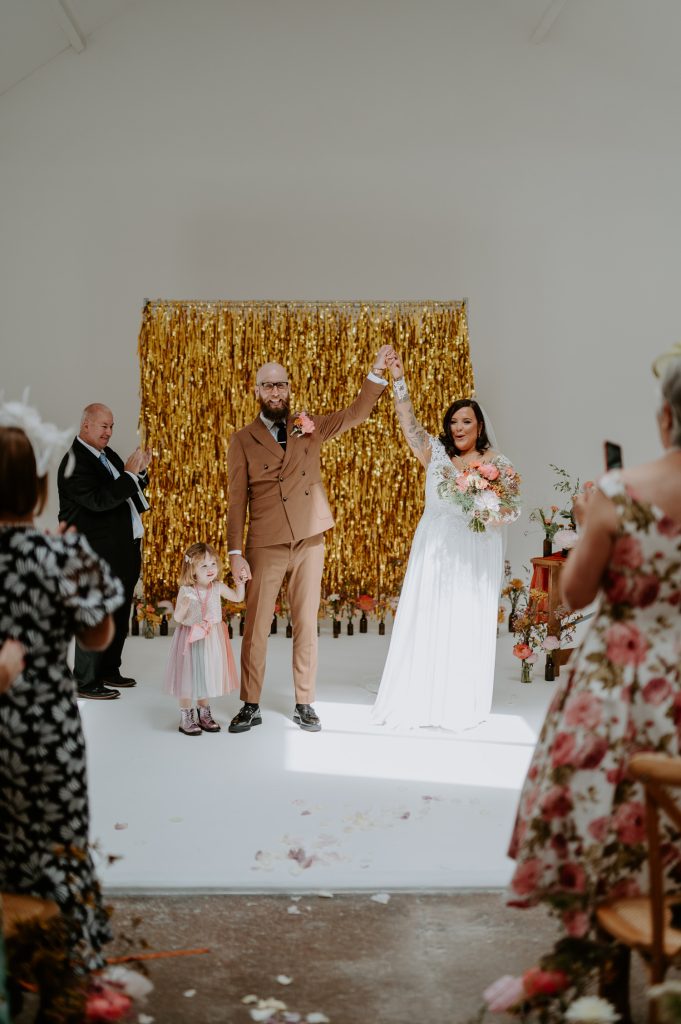 A bride and groom cheer as they are married at Five Four Studios.