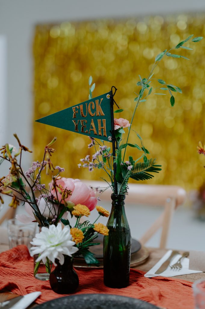 Green mini flag saying FUCK YEAH in gold at a stylishly colourful wedding at Five Four Studios.