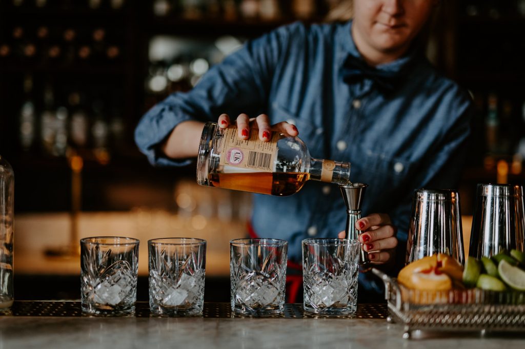 A bartender pours whiskey for a groom and his groomsmen before the wedding at Five Four Studios.