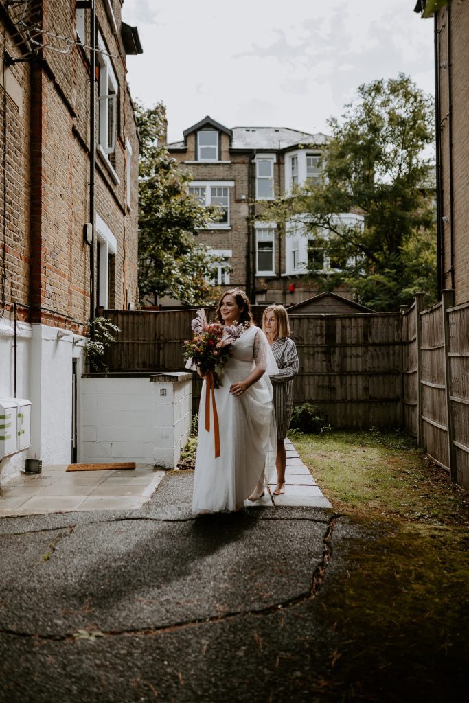 Bride and her mother walk around the corner for first look with the groom.