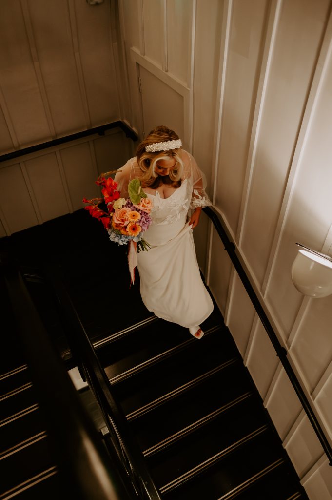 Bride walks down the stairs at Soho house to do a first look with her soon to be husband.