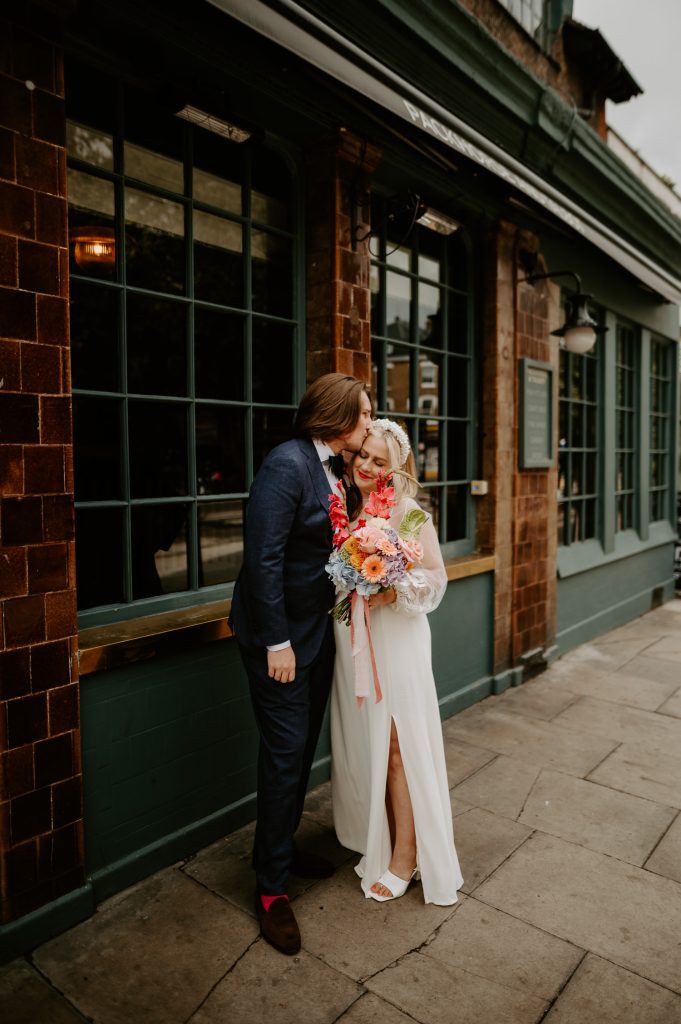 Groom kisses bride during their first look outside Soho House.