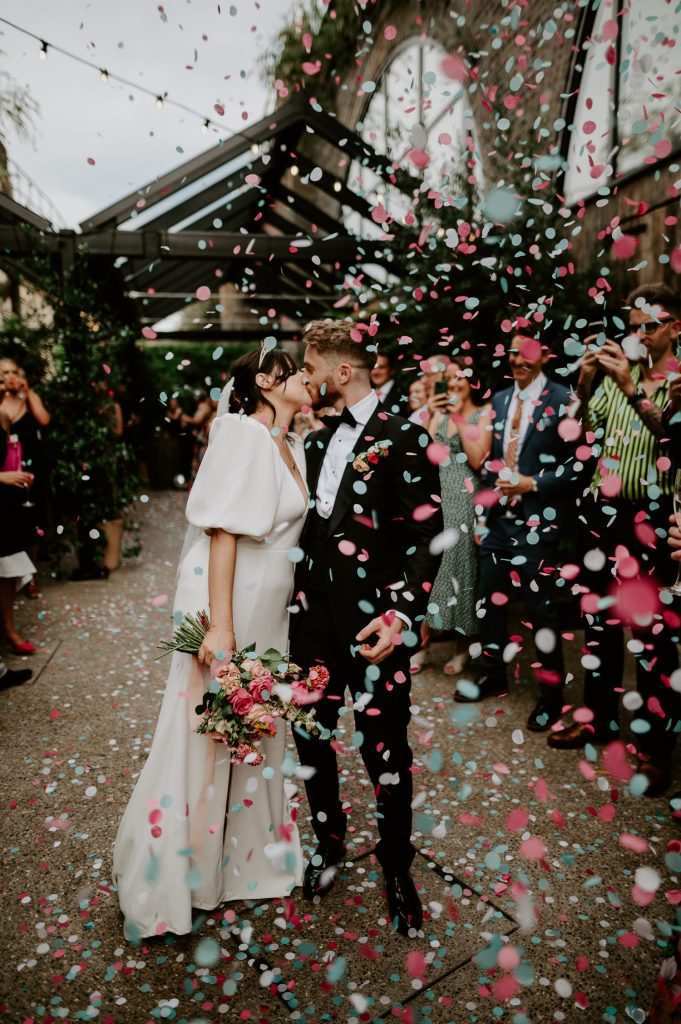A bride and groom kiss in a blizzard of confetti at 100 Barrington in London.