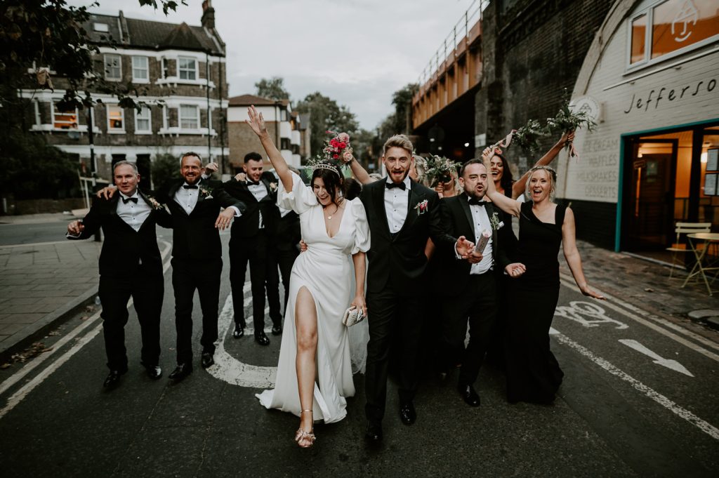 Wedding couple and their wedding party walk through the streets o Brixton.