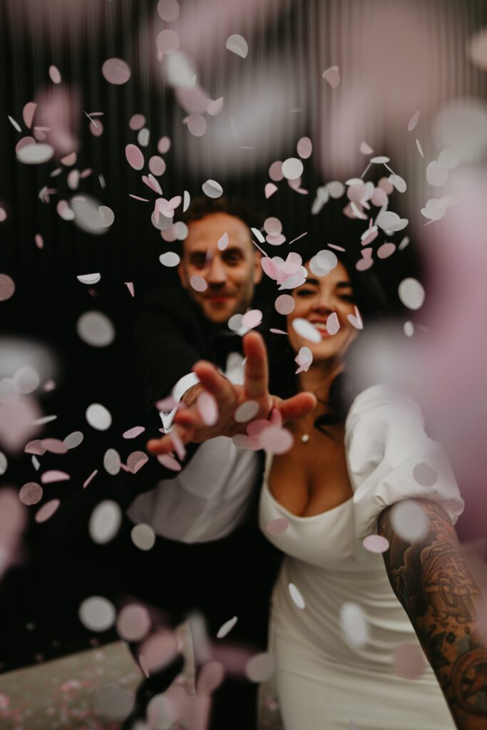 A bride and groom throw pink biodegradable confetti at the shack revolution. 