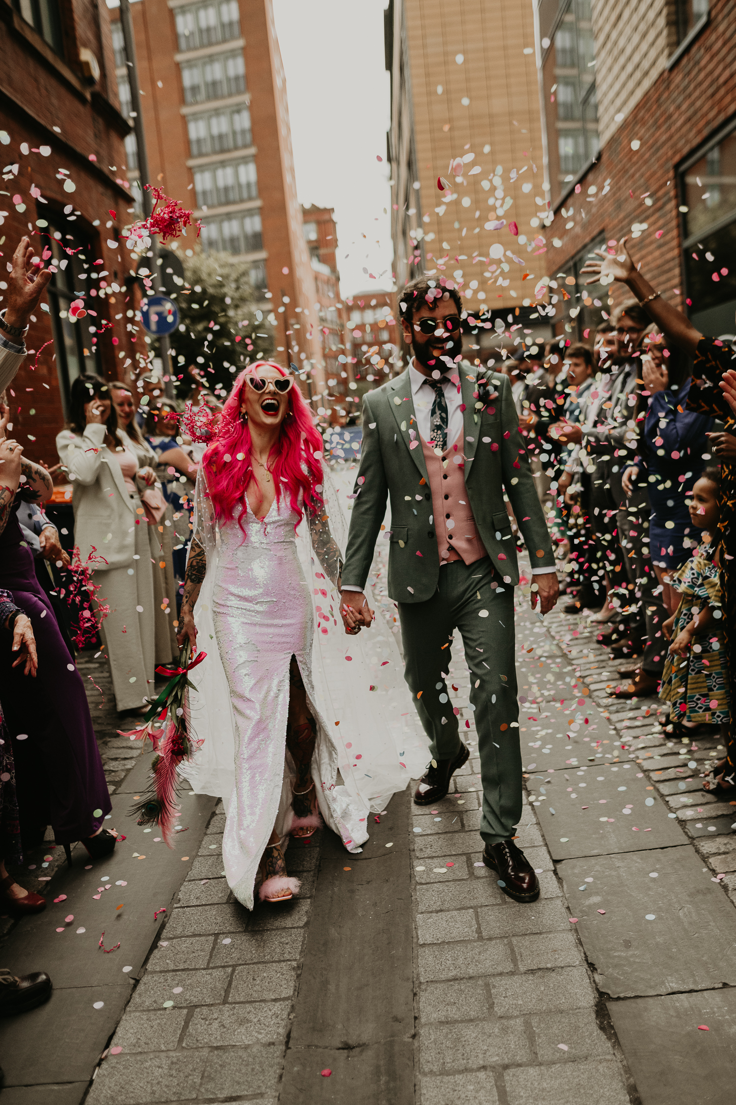 Bride and groom walk through confetti tunnel at their Manchester wedding.