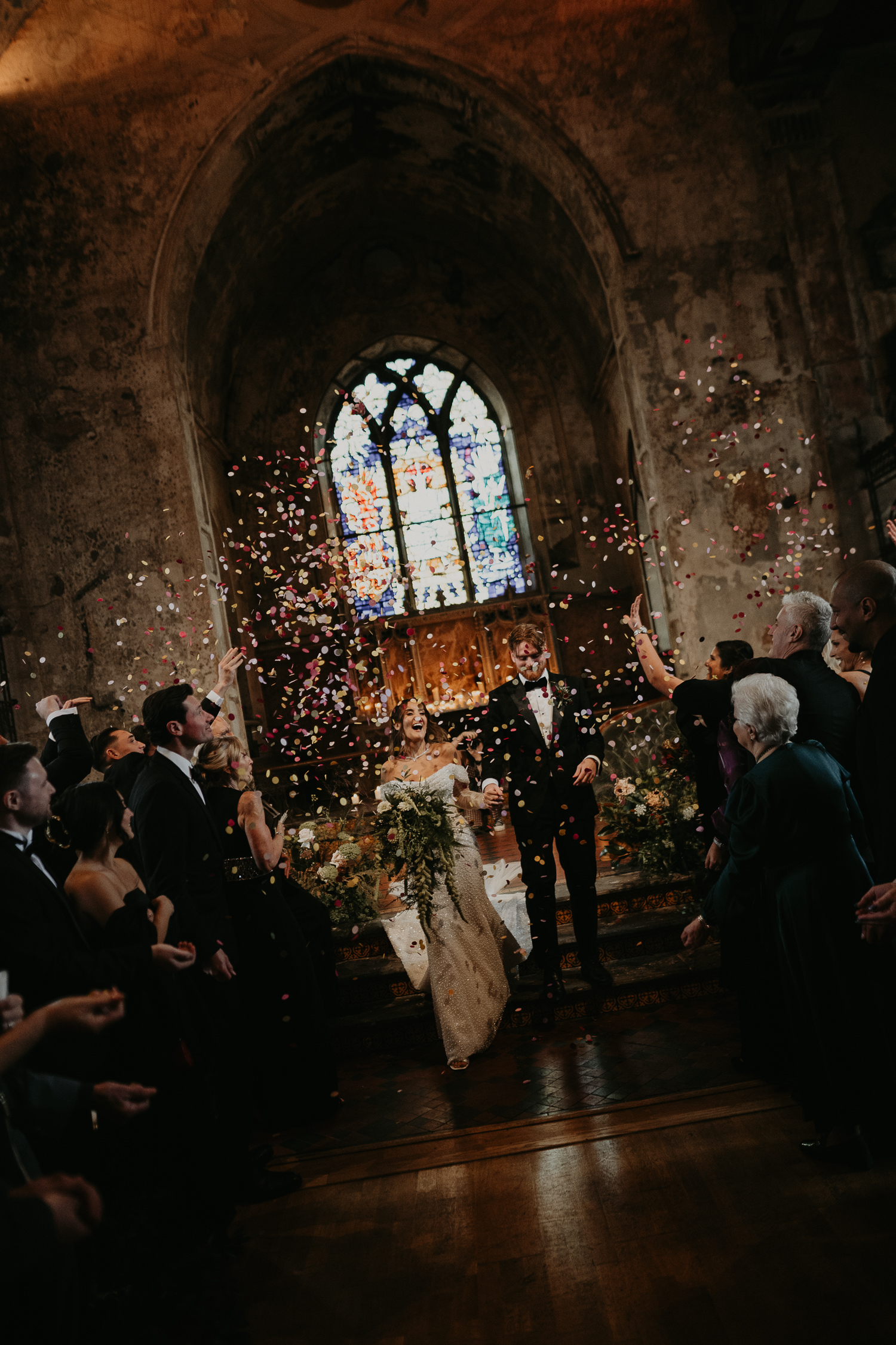 Bride and groom walk up the aisle as their wedding guests throw confetti at The Mount Without in Bristol.